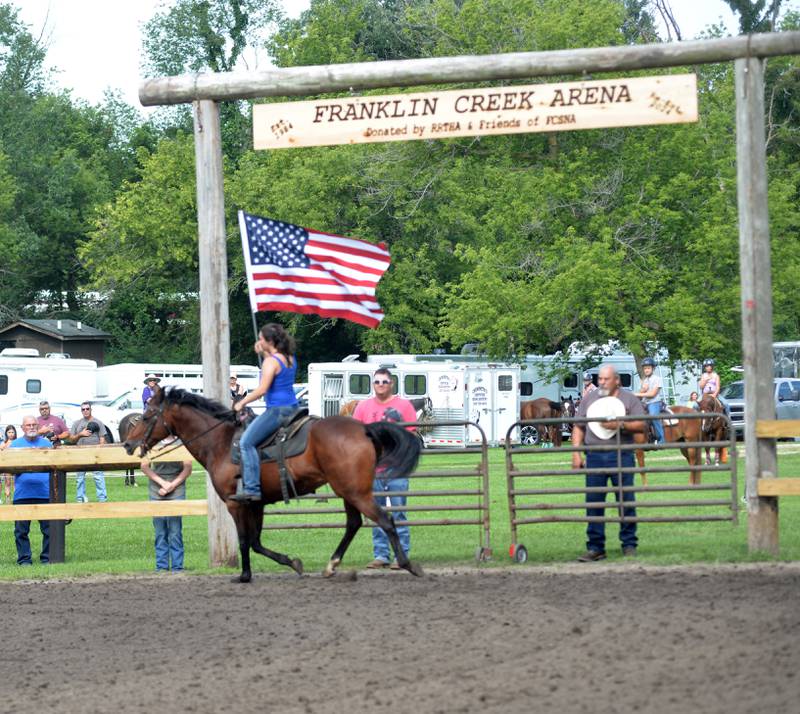 Evie Helton of Sycamore and a member of the Ogle County 4-H Horse Drill Team, carries the American flag as the National Anthem is played at the start of the Rock River Trail & Horseman Association's Grand Opening Show on Saturday, July 20, 2024. The show was held in the newly refurbished horse arena located in Franklin Creek Natural Area, just north of Franklin Grove.