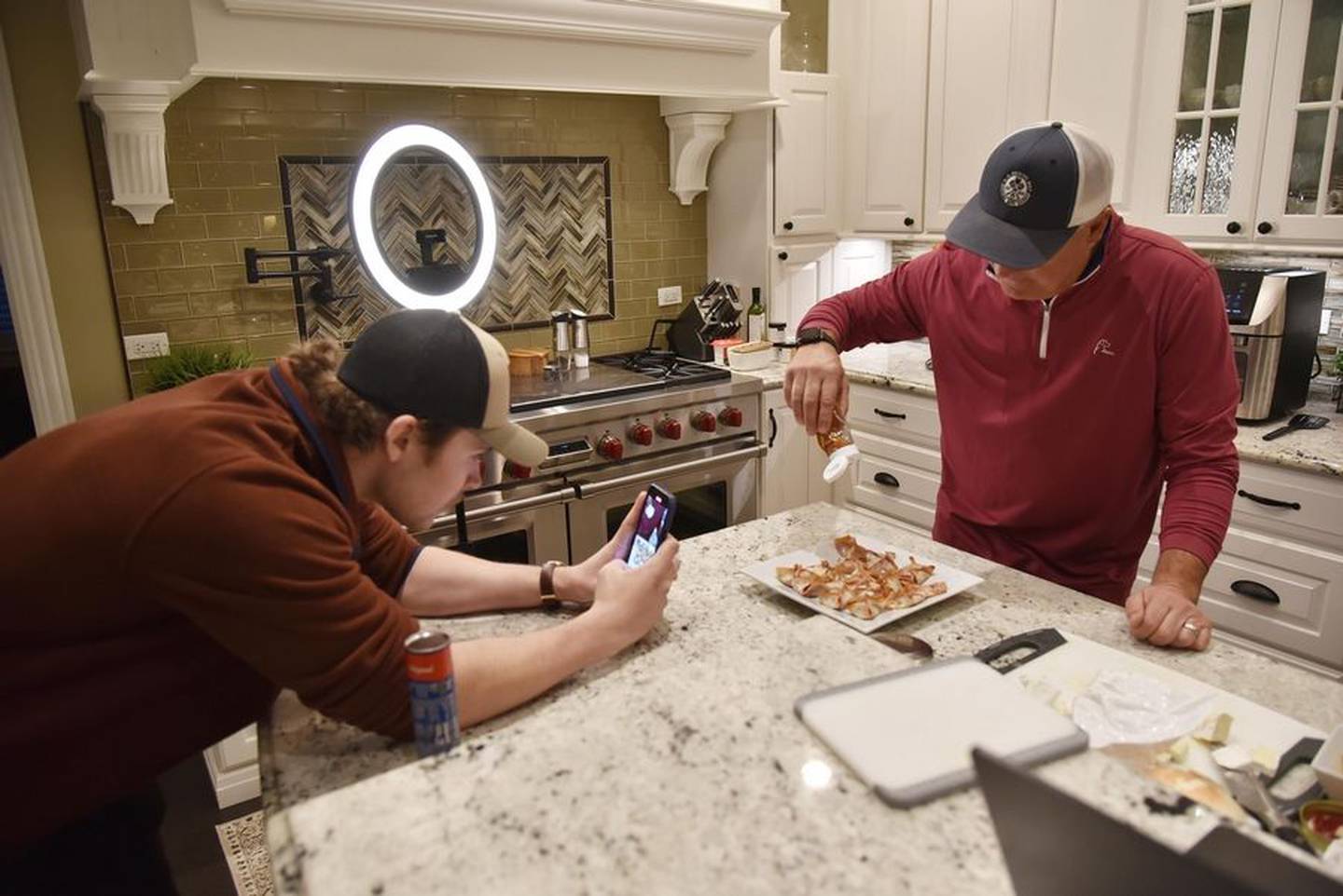 Intern Jake Konieczka, a North Central College student in Naperville, records Darryl Postelnick as he makes a social media cooking video in his Algonquin kitchen.