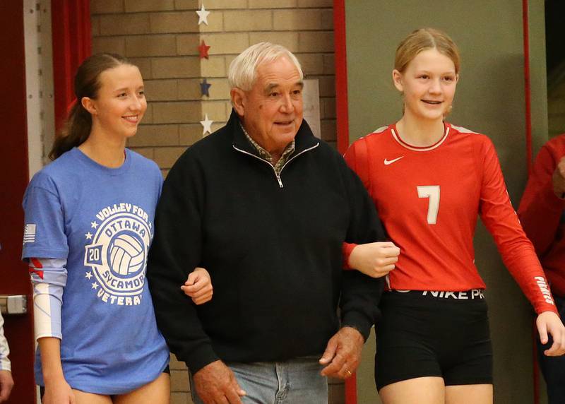 Marine Veteran Bruce Muffler is escorted by his granddaughters Alya Dorsey and Libby Muffler during the Volley for Vets presentation before the volleyball game against Sycamore on Thursday, Oct. 12, 2023 at Kingman Gym.