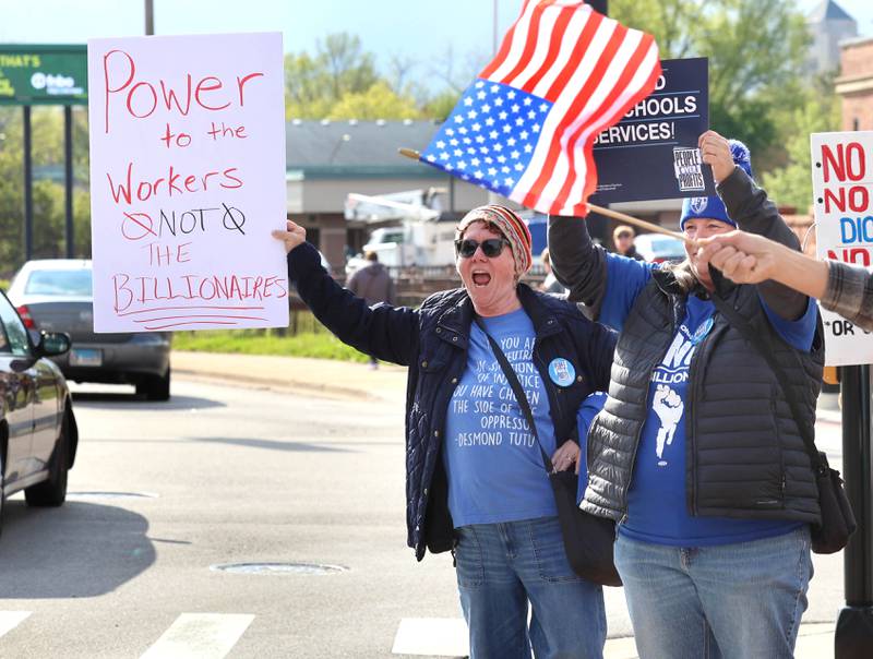 Protesters get the attention of passing vehicles Friday, May 1, 2026, during a May Day rally at Memorial Park in downtown DeKalb. The group gathered to advocate for workers’ rights and push for billionaires to be taxed amid cost-of-living burdens they argue are hurting everyday Americans.