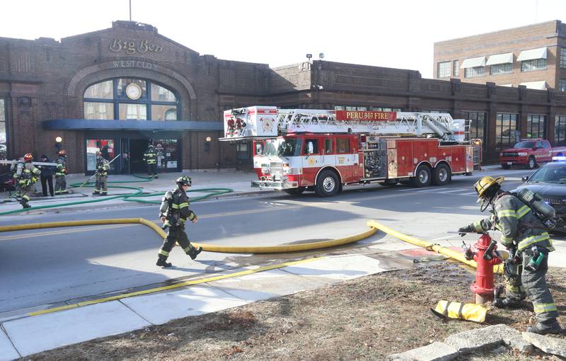 Firefighters charge a second line outside of Fire On Fifth in the Westclox building on Tuesday, Jan. 20, 2026 in Peru. A working fire started in the storage room inside of Fire on Fifth. The fire started at 10a.m.  Fire departments from Utica, Oglesby Peru and La Salle all assisted on the scene. La Salle and Peru EMS were also dispatched. The entire Westclox building was evacuated. Two employees were transported by ambulance for smoke inhalation. A smoke detector inside Star Union Spirits triggered an alarm, prompting a fast response from firefighters.