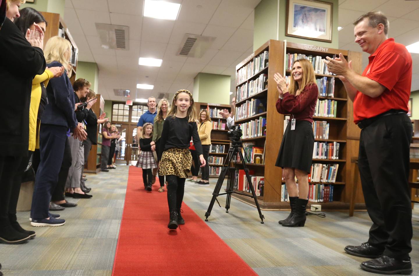 Author Reese Carney 8, of Utica walks down a red carpet with her father Pat, mother Emily and sister Avery, in McCormack Memorial Library to release her new book titled "Reeses Fantastic Surgery Adventure" on Monday, Nov. 6, 2023 at La Salle-Peru Township High School.