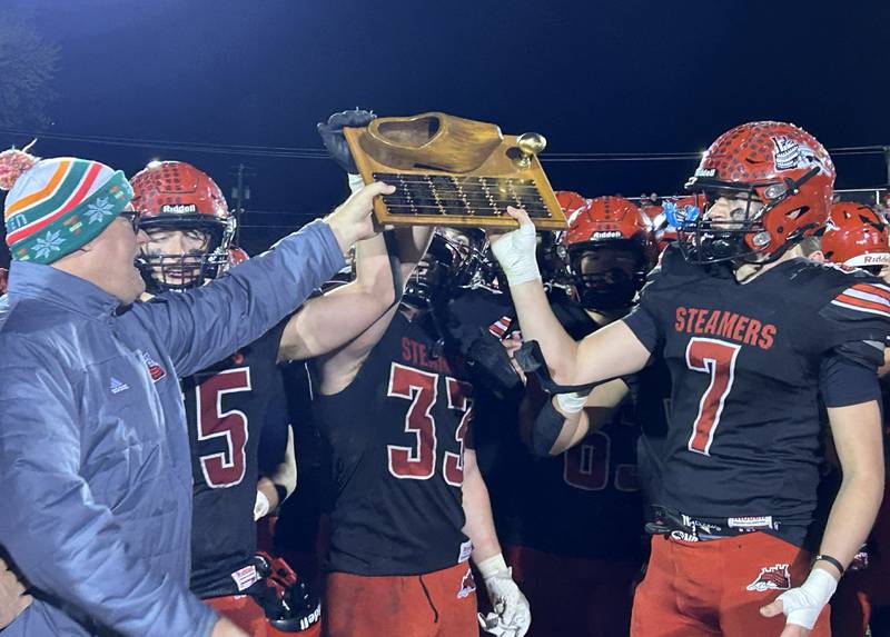 Fulton High School Athletic Director Roy Borgman presents the traveling Wooden Shoe Trophy to the Steamers eniors Josiah Heald (55), Skylier Crooks (33), Jacob Huisenga (7) after their 41-7 win over Morrison on Friday, Oct. 25, 2024.