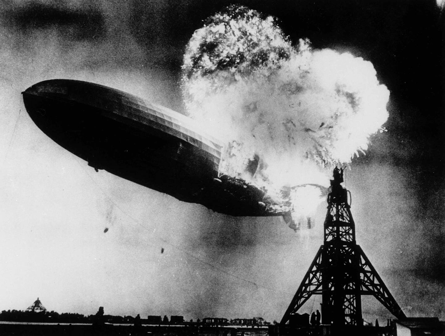 This May 6, 1937, file photo, taken at almost the split second that the Hindenburg exploded, shows the 804-foot German zeppelin just before the second and third explosions sent the ship crashing to the earth over the Lakehurst Naval Air Station in Lakehurst, N.J. The roaring flames silhouette two men, at right atop the mooring mast, dangerously close to the explosions. Thirty-five people on board and one ground crew member were killed.