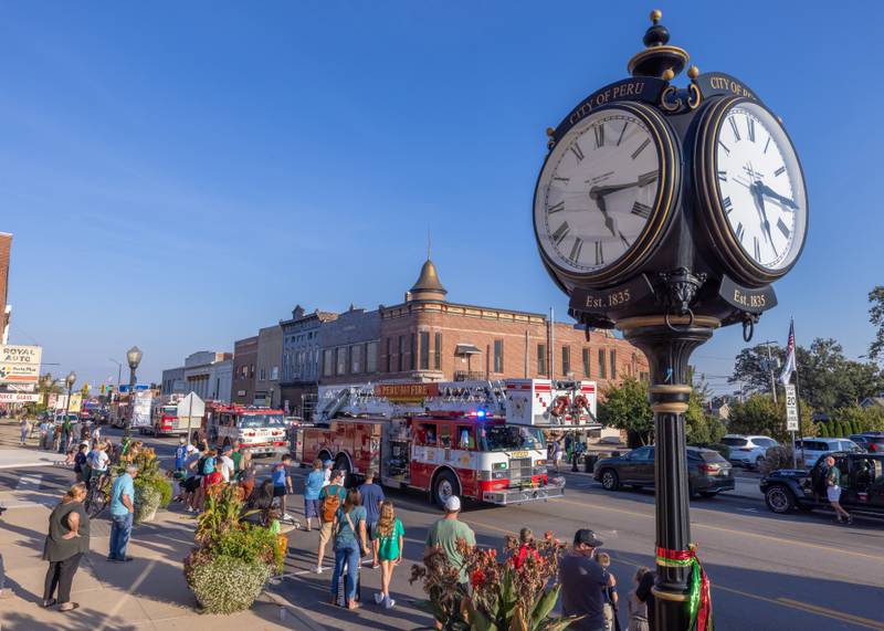 Spectators watch as the start of the St. Bede Homecoming parade nears city hall during the St. Bede homecoming parade on October 3, 2025 in Peru.