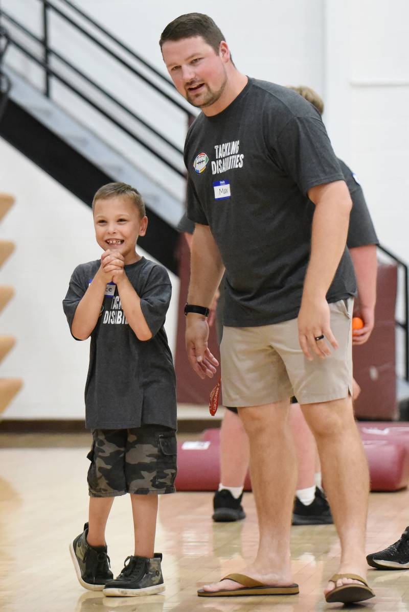 Pierce Storm, left, is all smiles as he stands next to Watseka football coach Max Fransen before performing a drill at the school's Tackling Disabilities football camp Saturday, July 26, 2025.