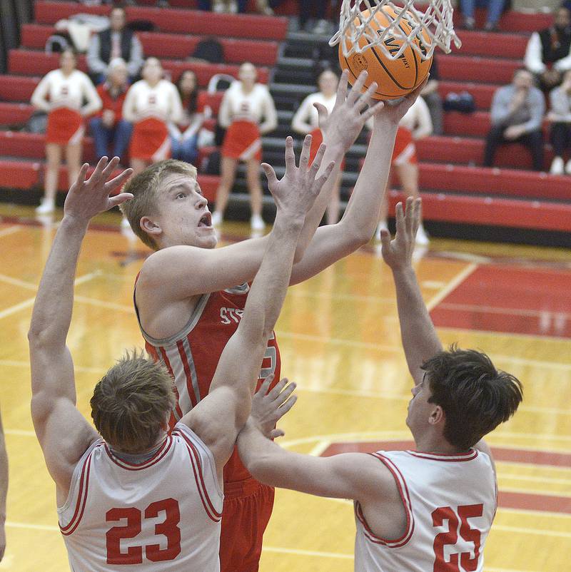 Streator’s Joseph Hoekstra reaches up past Ottawa’s Owen Sanders and Lucas Farabaugh for a layup in the 1st period Saturday at Ottawa.