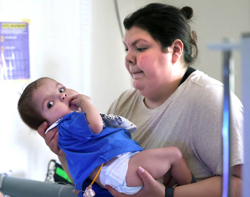 Kassandra Santos picks up her daughter Marely, 1, Monday, June 30, 2025, at their home in DeKalb. Marely was born with a myriad of health issues that require around-the-clock care and recently received a heart transplant.