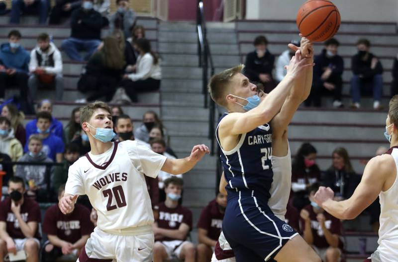 Prairie Ridge’s Jackson Otto, left, keeps his eyes on the action as Cary-Grove’s Ryan Zielinski scrambles for a rebound during boys varsity basketball action in Crystal Lake Tuesday night.
