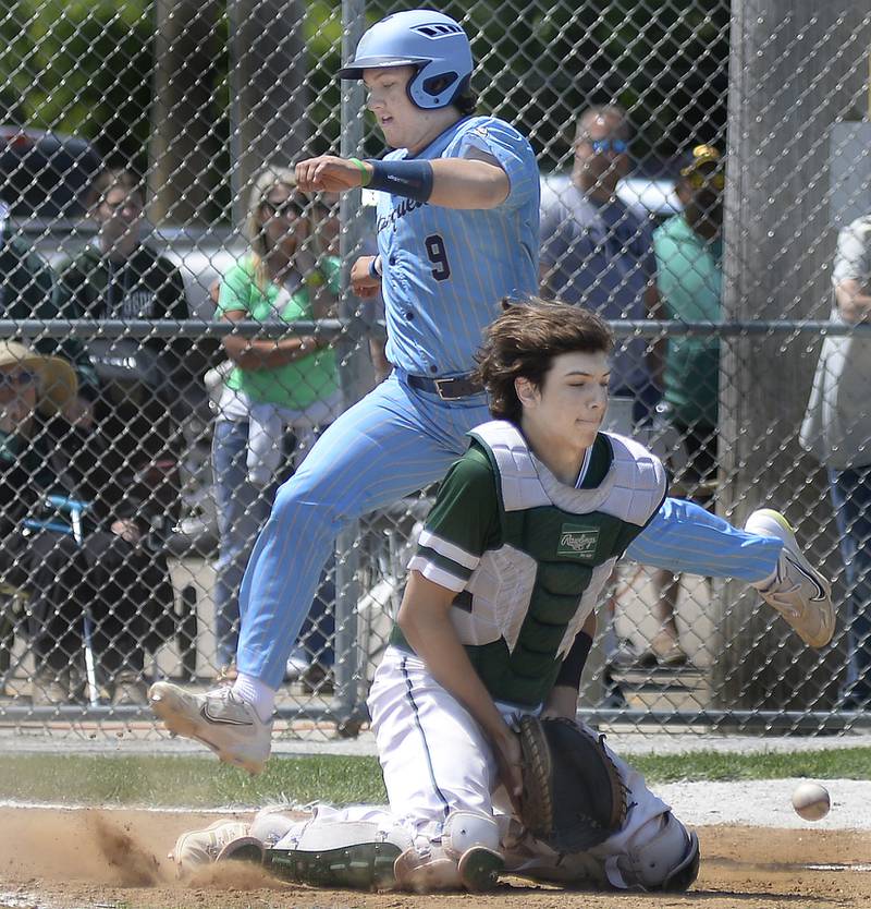 Marquette’s Alex Graham hops over St Bede catcher Nathan Husser awaiting a short hop throw to the plate to score on Saturday, May 20, 2023 at Masinelli Field in Ottawa.