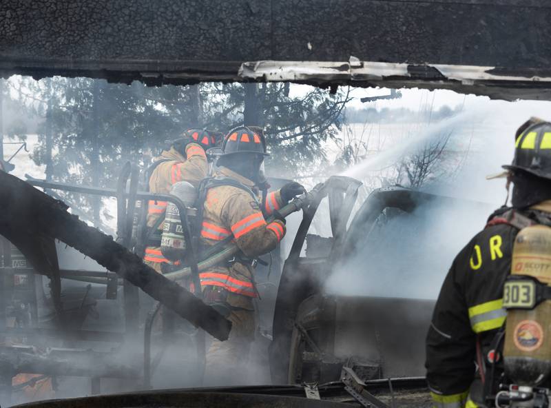 Firefighters from several area departments extinguished a garage fire at 7483 E. Husking Peg Road on Friday, Feb. 14, 2025. Here, firefighters hose down a vehicle that was inside the charred remains of the detached garage.