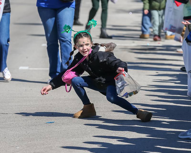 A young girl retrieves thrown candy during the Lemont St. Pat's Day Parade on Saturday, March 8, 2025  in Lemont.