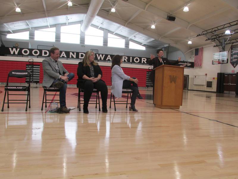 Woodland hall of fame inductees (left to right) Michael Mallick, Kristine Metzke and Jan (Appel) Holmes look on as Jessica Wicks talks to students Friday, April 14, 2023, during an assembly at the Woodland gymnasium.
