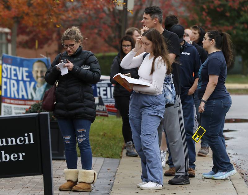 Jodie Hanrahan (center) studies for one of her college classes as she waits in line to vote with others on Monday, Nov. 4, 2024, at the McHenry City Hall in McHenry.