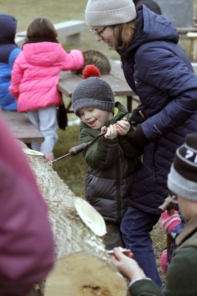 Five-year-old Michael Cafferty of Wheaton gets some help from his mom Karen, during a maple sugaring event at Kline Creek Farm Saturday March 11, 2023 in West Chicago. The annual program helps people discover how sap becomes syrup as you try tapping with tools from the 1890s, check the collection buckets, watch sap thicken over the fire, and try a taste of real maple syrup.