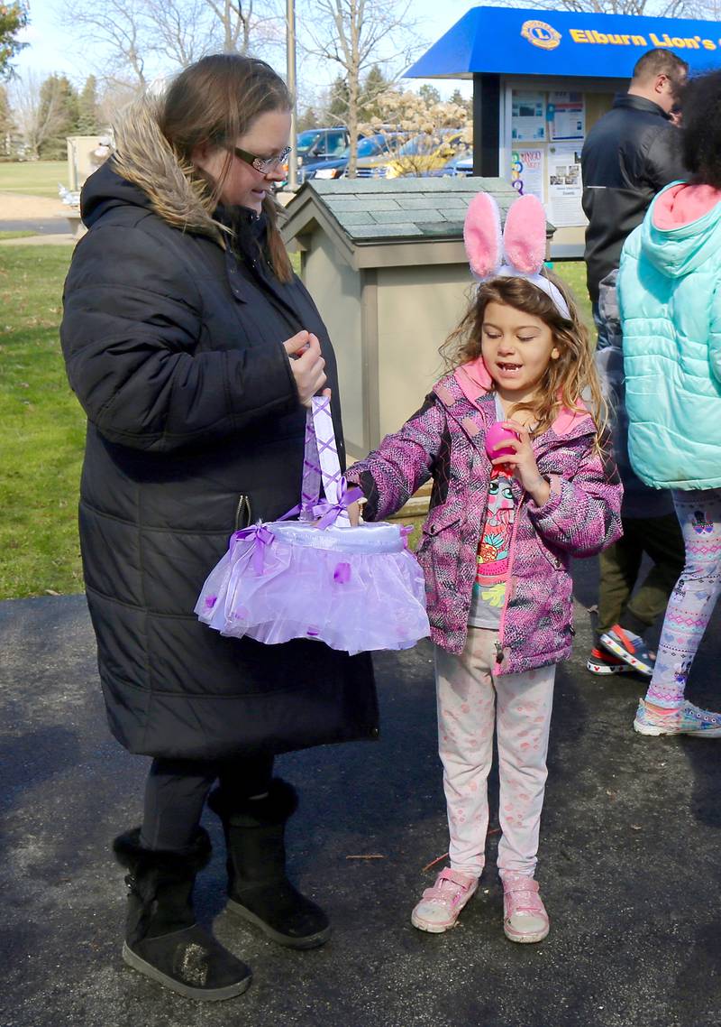Toni Flores holds an Easter basket while Sophia Flores, 8, puts eggs in it that she has collected during the Easter Egg Hunt at the Lion’s Club in Elburn on Saturday, April 9, 2022.