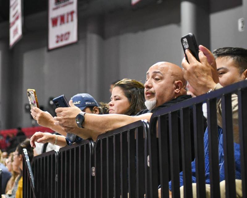 Friends and family hold signs and record video of their senior graduates on Saturday, May 24, 2025, during the Class of 2025 Commencement ceremony held at the NIU Convocation Center in DeKalb.