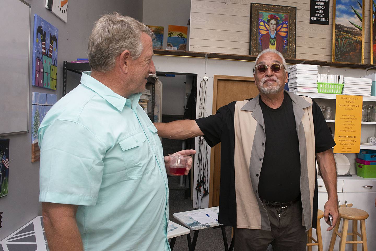 Artist Robert Valdez (right) greets Breck Loos Monday, Aug. 29, 2022 during a reception for Valdez who has been working to renovate the hispanic heritage mural “Adelante” that he first painted 20 years ago. The mural is painted on the side of the Napa Auto Parts building that Loos owns and built. The store had only been up for a year before the mural society approached Loos about painting the work on the empty wall.