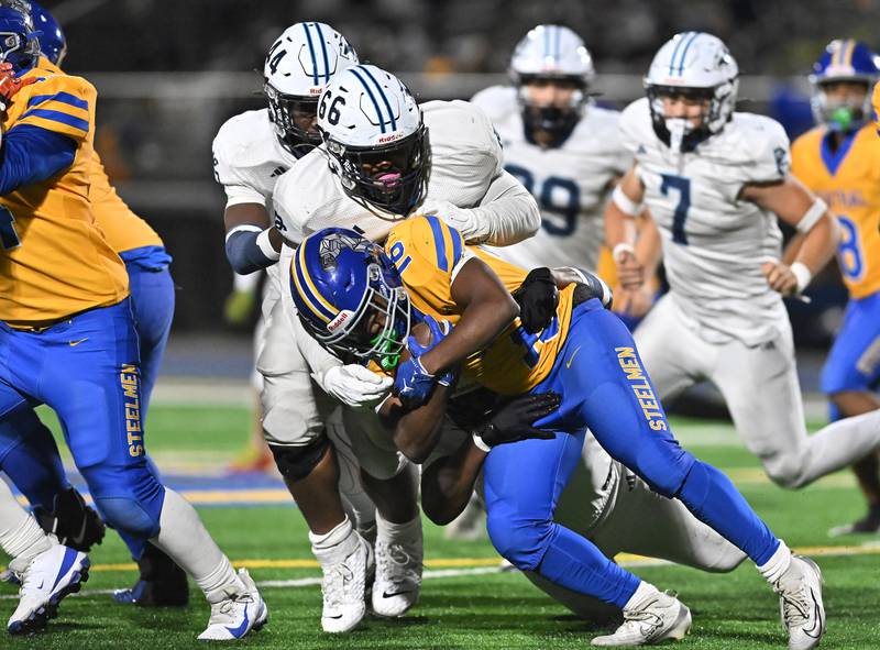 Joliet Central's Tristen Sellers (18) gets tackled by Plainfield South's Rory Falconer (66) during the conference game on Friday, OCT. 17, 2025, at Joliet.