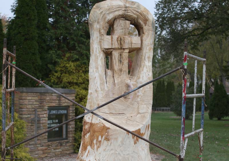 Bud Hainzinger of Morris carved a cross in a tree stump at St. Johns Lutheran Church on Friday, Nov. 3, 2023 in Peru. The family of Don and Ruth Johnson donated the cost of the tree carving in memory of their parents.