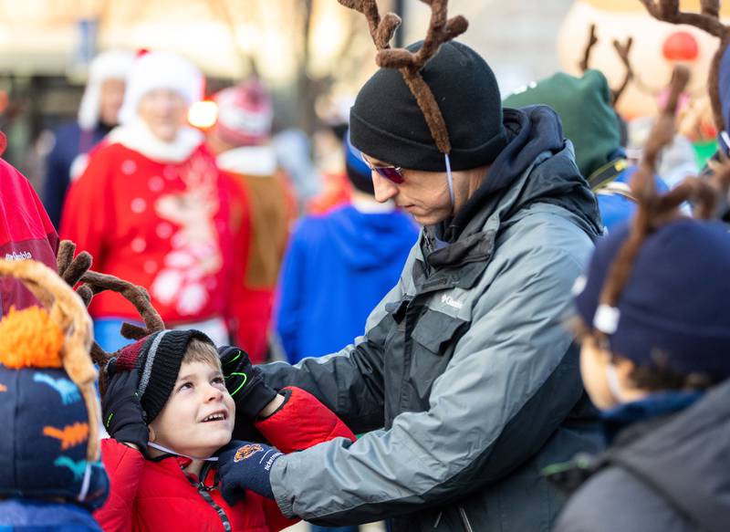 Geoff Matteson, right, helps his son Joshua Matteson, 6, put his reindeer antlers on before the 13th annual Lions Charities Reindeer Run 5K Wheaton on Saturday, Dec. 7, 2024.