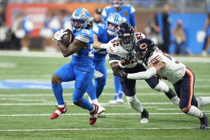 Detroit Lions running back Jahmyr Gibbs (26) runs the ball as Chicago Bears linebacker T.J. Edwards (53) and Darrell Taylor (52) defend during the first half of an NFL football game, Sunday, Nov. 17, 2024, in Detroit. (AP Photo/Carlos Osorio)