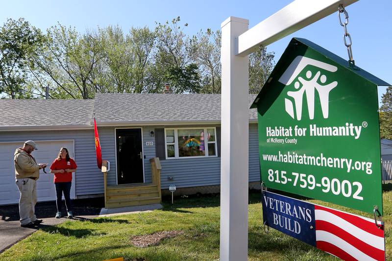 Construction manager Bill Lee, left, and volunteer coordinator Allison Dibbern, both of Habitat for Humanity of McHenry County, talk in the front yard during a home dedication ceremony for Mike Kopala, a Vietnam-era Marine Corps veteran from Lake in the Hills, on Saturday, May 29, 2021 in McHenry.  The project rehabilitated the existing residence to include a new garage, updated plumbing, heating, energy-efficient windows, and more.