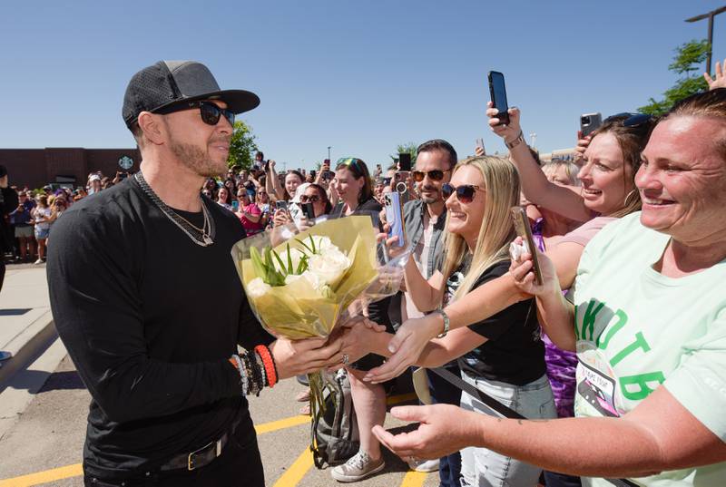 Donnie Wahlberg receives flowers from Jamie Rankin of Ohio as he greets fans before the Wahlk of Fame Ceremony for New Kids on the Block at the Wahlburgers in St. Charles on Saturday, June 18, 2022.