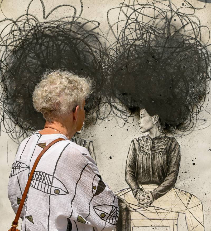 A woman views an art piece by May Mayhew during the Geneva Arts Fair along Third Street on Saturday, July 27, 2024.