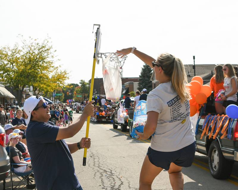 Assistant varsity softball coach Tiffany Murphy dunks on Paul Villanueva’s Oswego candy hoops during Oswego High School homecoming parade on Sunday Sept. 15, 2024, that traveled through downtown Oswego.