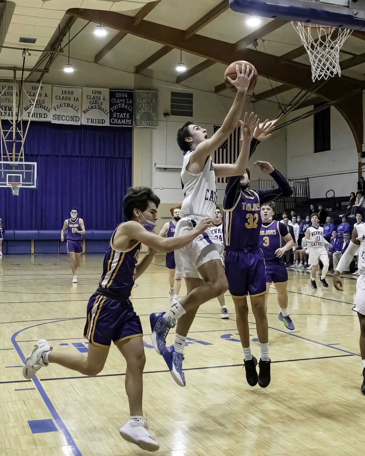 Newman's Jacob Donald goes in for a layup between a pair of Mendota defenders during their Three Rivers East game Friday night in Sterling.