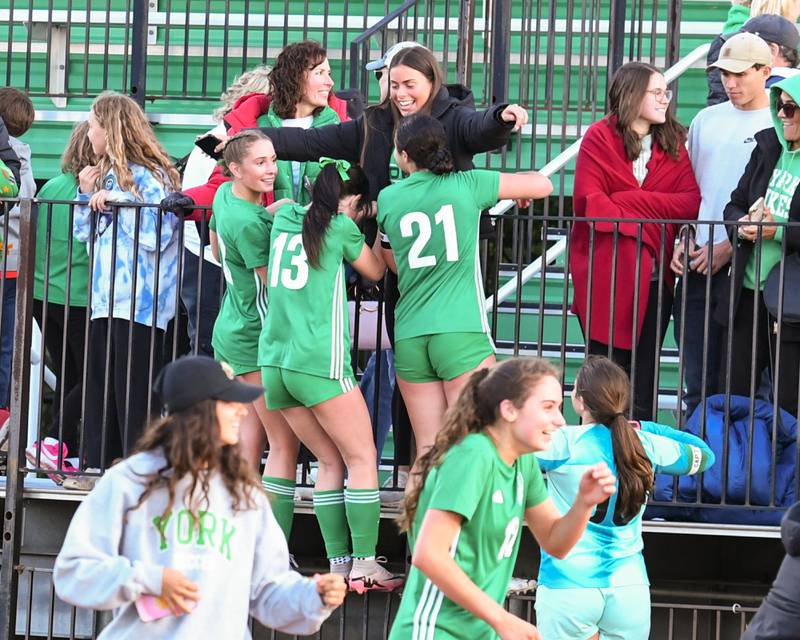 York soccer teammates Maggie Quinn, left, Jordan Ebner, center and  Andrana Soupos (21)  get a congratulations hug from fans in the stands after defeating Downers Grove South in the regional title game on Friday May 23, 2025, held at York High School.