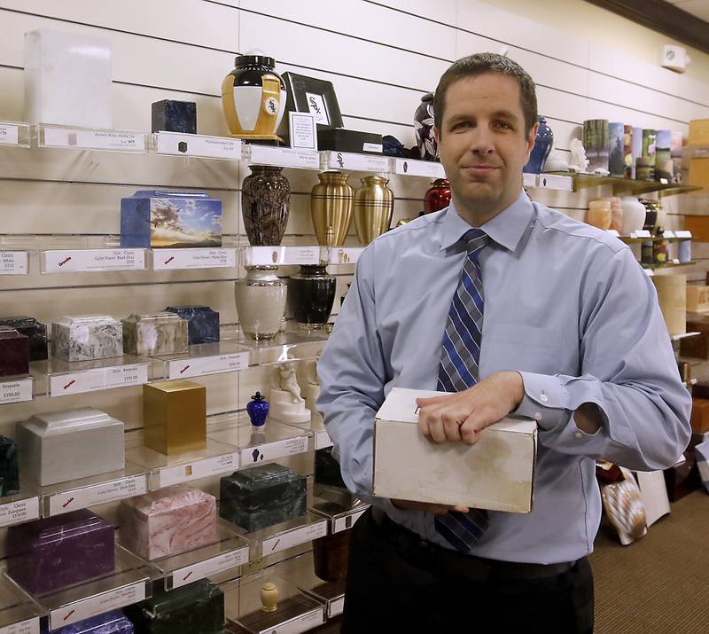 Robert Justen of Justen Funeral Home & Crematory holds the cremated remains of a person who was returned to the funeral home after many years for burial.