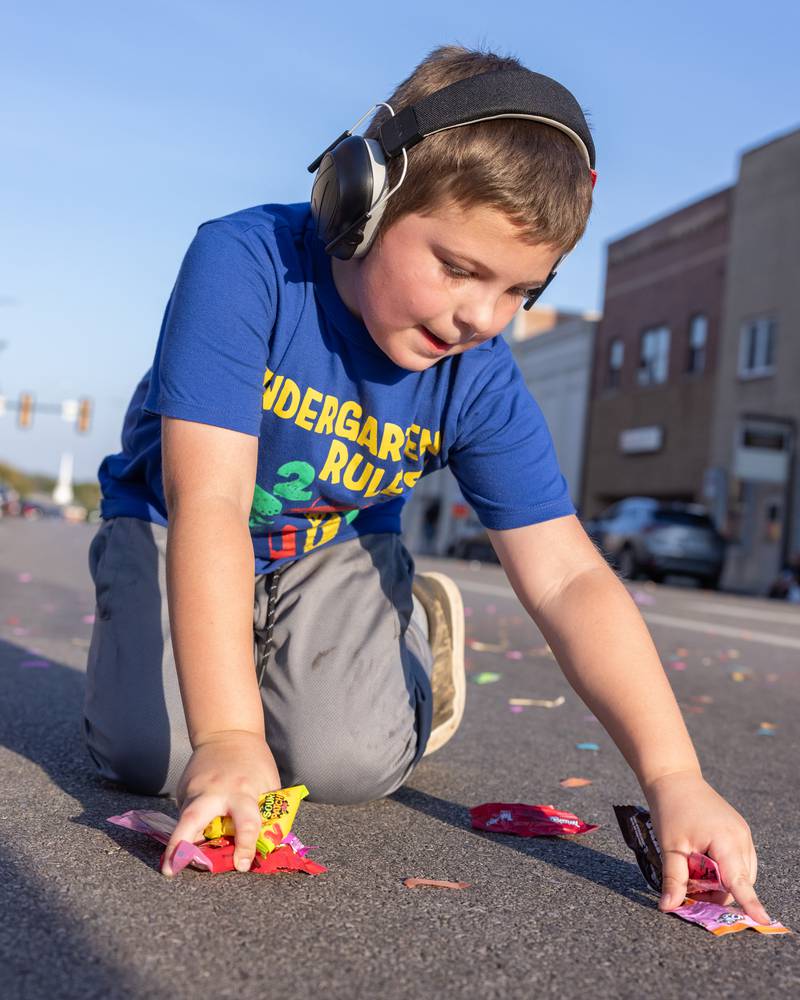 A young parade spectator grabs as much candy as he can possibly hold during the St. Bede homecoming parade on October 3, 2025 in Peru.