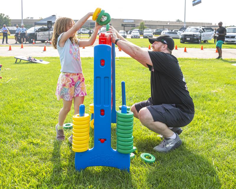 Todd Ekard plays a game with his daughter Keira at the Joliet Police Department's National Night Out event Tuesday, Aug 5, 2025  in Joliet.