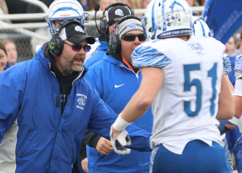Princeton football head coach Ryan Pearson hi-fives player Landyn Kendall after making a play during the Class 3A playoffs on Saturday, Nov. 1, 2025 at Central Catholic High School in Bloomington.