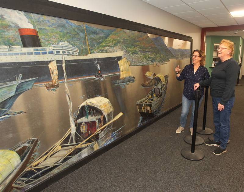 Candace H. Johnson for Shaw Local News Network
Amy Whitis, interim Parks & Recreation manager, talks with Nancy Kleszynski, of Woodstock about the Buell Mullen mural on display at the Lakefront Park building in Fox Lake.The mural titled, "Hong Kong," features a view of the Hong Kong harbor and is on loan from the National Museum of the American Sailor. It is approximately 20 ft. long and six-feet high on stainless steel and weighs about 600 pounds. This is one of a two pieces in a mural set with the other piece on display at the County Building in downtown Waukegan. (10/31/22)