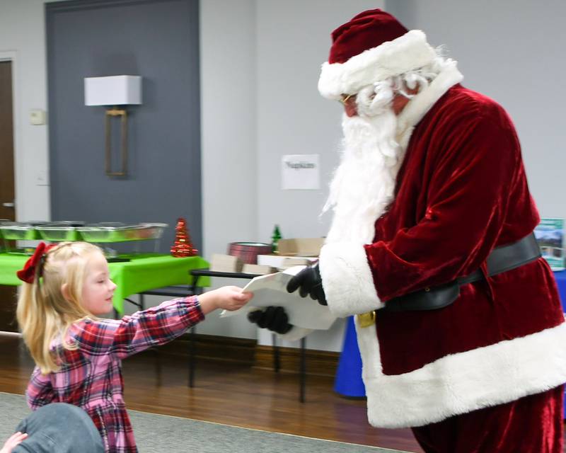 Caoimhe Shields, 5, of La Grange hands her Christmas list to Santa during the breakfast with Santa event held on Sunday Dec. 15, 2024, at the La Grange Park District Recreation Center.