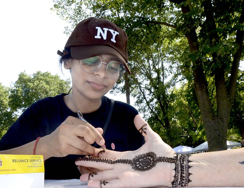 Bhawana applies a henna tattoo for a customer Saturday at Washington Park in Ottawa during the 4th annual Children’s Business Fair.