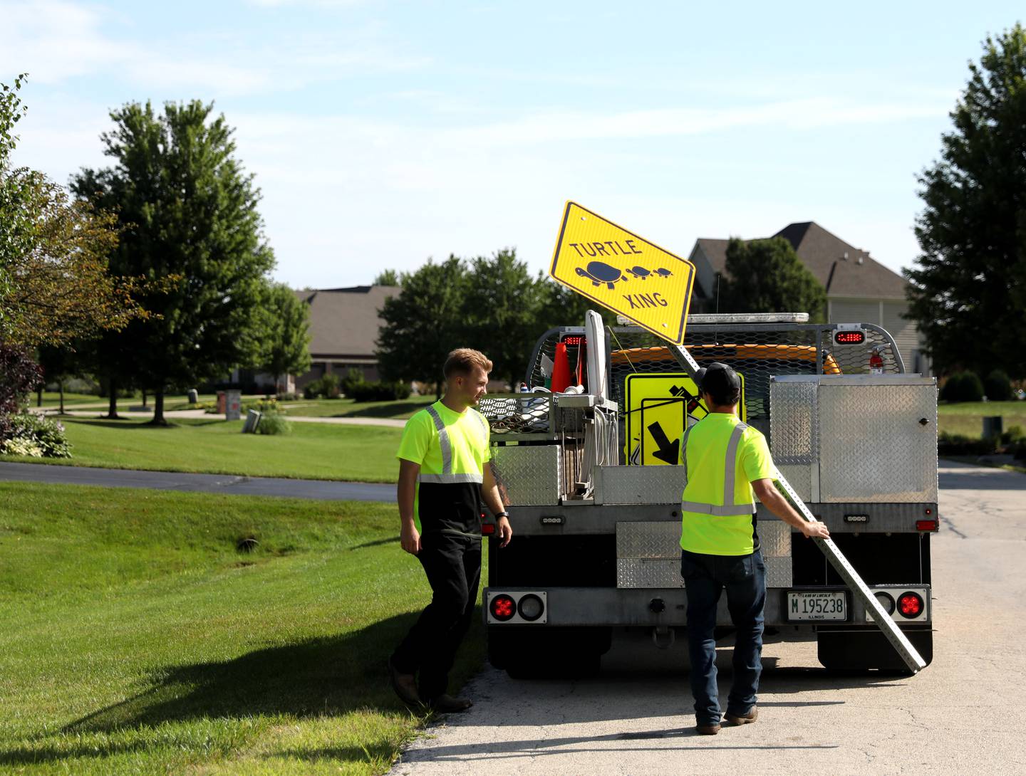 Austin Thomas (left) and Ryan Schramer (right) of the Campton Township Highway Department intall a Turtle Crossing Sign on East Sunset Views Drive in Lily Lake on Monday, July 8. 2024. Turtle Crossing signs were installed after neighborhood families came together to fund the project in an effort to protect their neighborhood turtles from vehicle traffic.