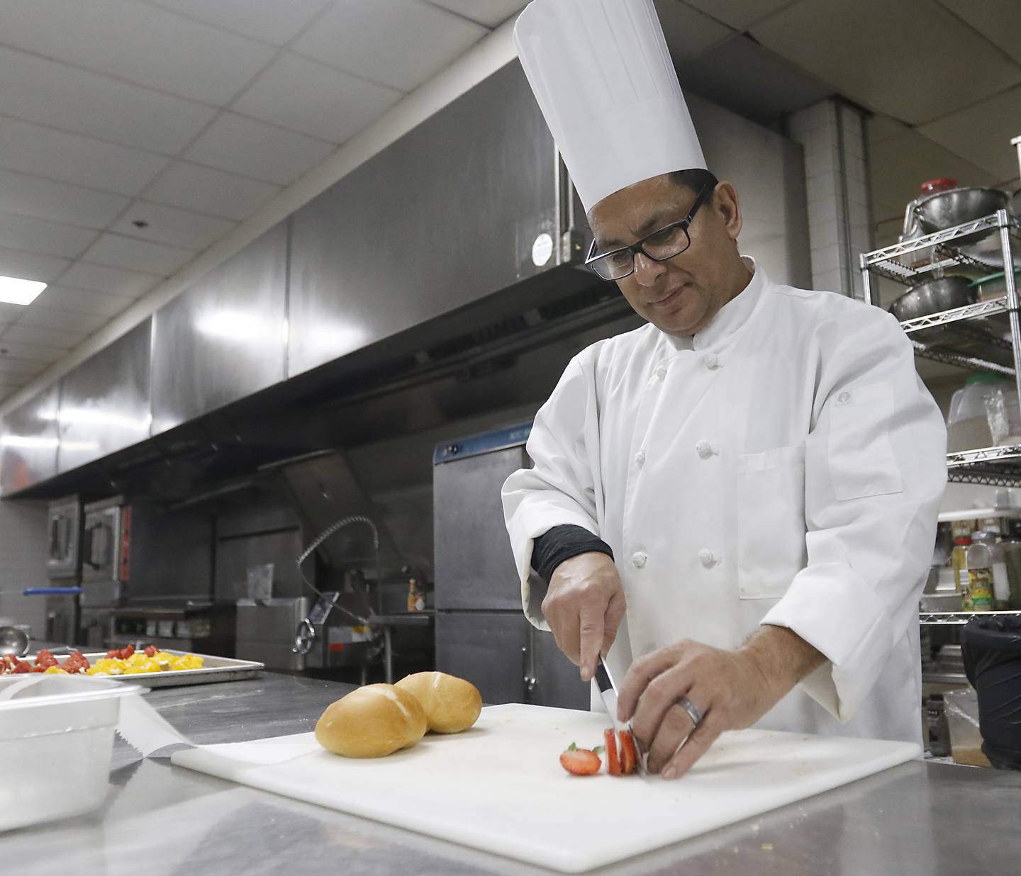 Chef Isaias Benitez slices a strawberry as he prepares food Friday, Dec. 16, 2022, at the Holiday Inn, 800 S. Route 31 in Crystal Lake, for a Christmas party at the hotel. In-person holiday parties have returned this year after several years of the COVID-19 pandemic curtailing parties.