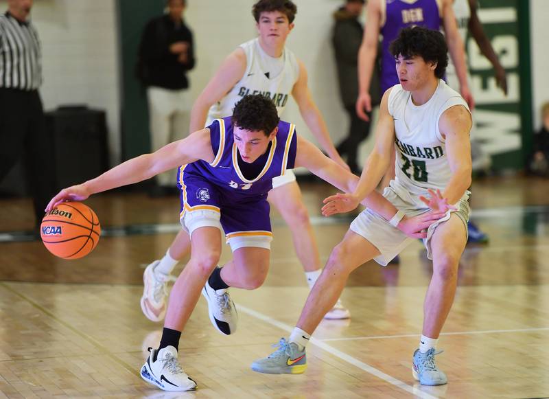 Downers Grove North’s Connor Crowley (left) tries to control the ball in the glare of the scorers’ table as Glenbard West’s Peter Carter (20) defends during a game on January 23, 2026 at Glenbard West High School in Glen Ellyn.