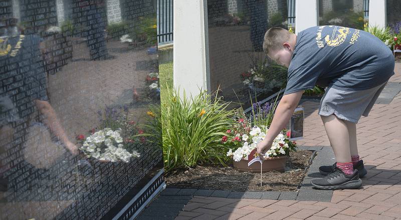 Volunteers place flowers and flags Saturday, June 17, 2023, along the Middle East Conflicts Wall in Marseilles after the Illinois Motorcycle Freedom Run.