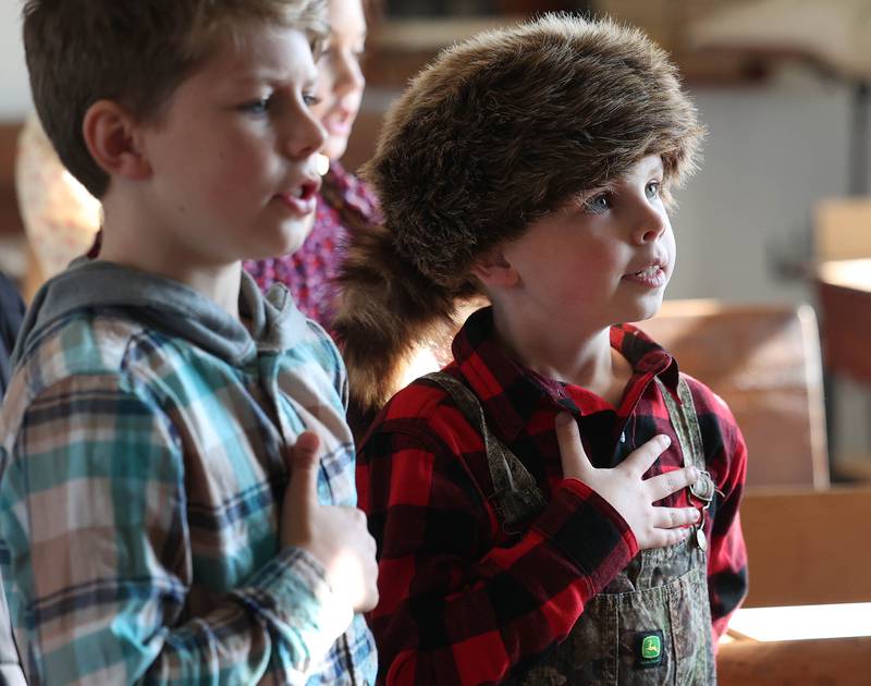 Southeast Elementary School third grader Cooper Tillman (right) says the Pledge of Allegiance in class Tuesday, Nov. 4, 2025, during a field trip to North Grove School, a one-room schoolhouse from 1878 in Sycamore.