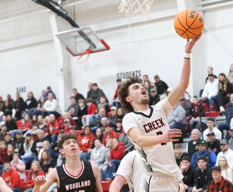 Indian Creek's Logan Schrader runs in for a layup over Woodland's Jaron Follmer during the Class 1A Sectional Semifinal game on Wednesday, March 4, 2026 at Amboy High School.
