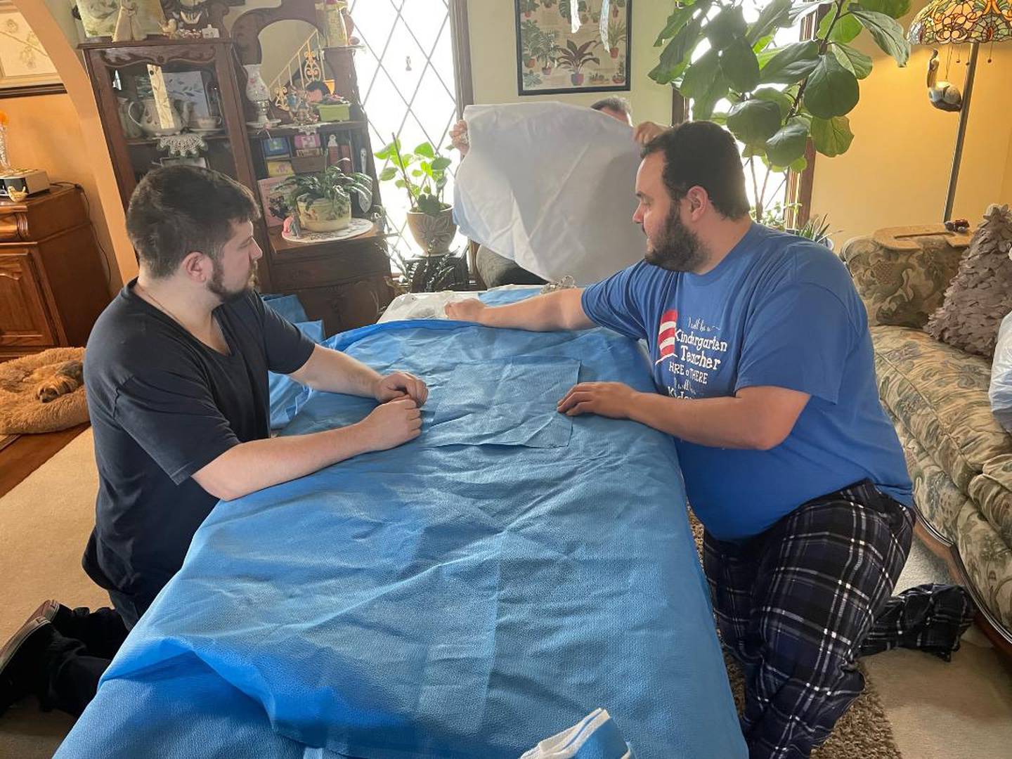 On Saturday, April 9, 2022, a small group of friends gathered at Kimberly Creasey's home in Joliet to create waterproof sleeping bags out of expired surgical drapes. The sleeping bags were sent to Poland, where they will be distributed to people from Ukraine in need. Pictured, from left, is Greg Aimaro of New Lenox and Michael Creasey of Joliet as they pin surgical drapes to prepare for sewing.