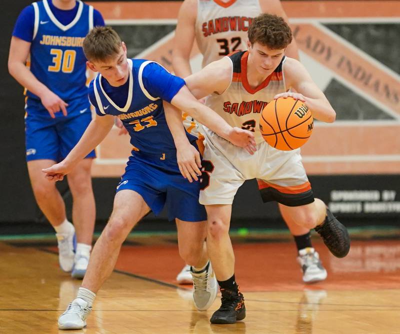 Johnsburg's JT Schmitt (33) attempts to steal the ball from Sandwich's Griffin Somlock (2) on the top of the key during a basketball game at Sandwich High School on Friday, January 31, 2025.