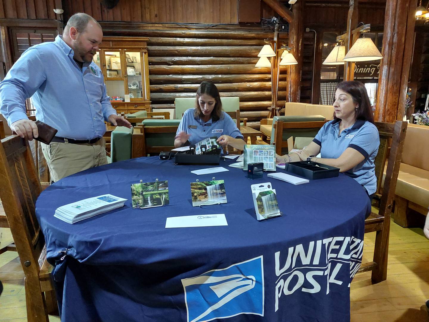 Nicole Gray (left), Utica postal clerk, and Amy Patyk, Oglesby postal clerk, sell books of the U.S. Postal Service's waterfall stamps, featuring La Salle Canyon waterfall at Starved Rock State Park. They sold the stamps at a ceremony Friday, June 30, 2023, at the Starved Rock Lodge and Conference Center.