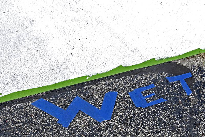 Wet marks a freshly painted parking spot on Tuesday, Aug. 13, 2024, as students work on painting their parking spots at the school in Woodstock.