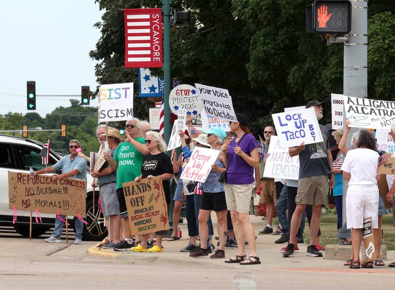 Protesters hold signs Saturday, July 4, 2025, at the corner of Main and State Streets in front of the DeKalb County Courthouse in Sycamore for a "No Kings" rally to voice their displeasure with President Donald Trump.